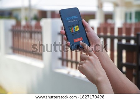 A woman's hand holds a smartphone with shoping online sign on phone screen at home. stay safe at home concept