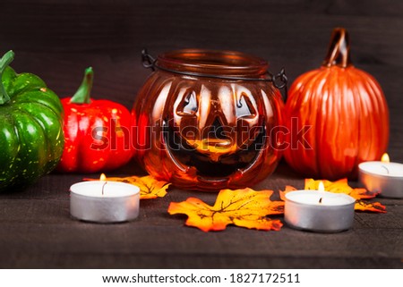 Halloween. Pumpkins glow in the dark. Still life with pumpkins, candles and autumn leaves on a wooden background