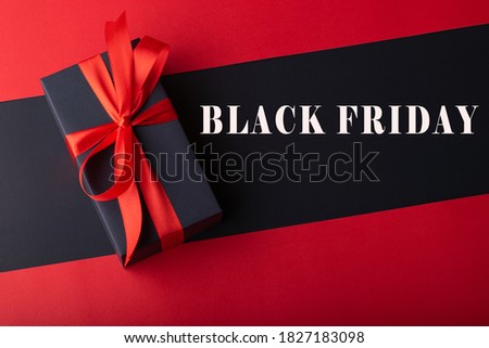 Top view of black boxes with red ribbon on black background and red background. Black Friday and Boxing Day.