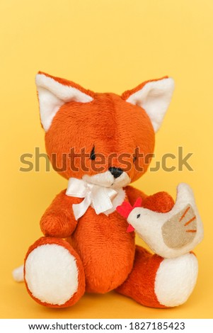 Soft toy ginger fox with chicken on a yellow background