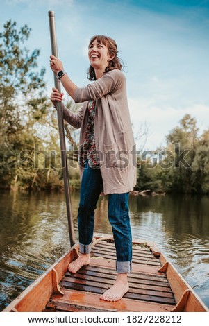 A beautiful young woman punts on a boat in a river in Oxford. Punting, Tourist, River, Boat.  Royalty-Free Stock Photo #1827228212