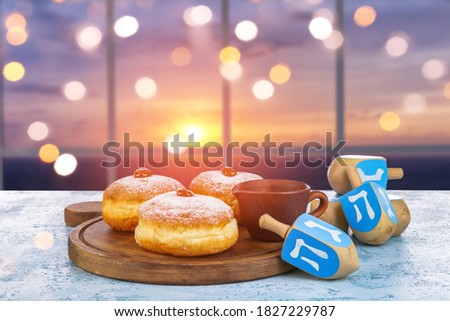 Donuts for Hanukkah and dreidels on table near window Royalty-Free Stock Photo #1827229787