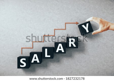 Hand holding salary word on cubes with arrow in form staircase. Trade and sale concept.