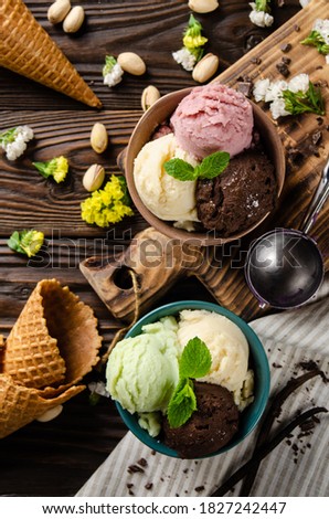 Different scoops of Vanilla pistachio chocolate and strawberry icecream balls in clay bowls on wooden kitchen table. Flat lay