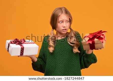 Image of charming blonde girl 12-14 years old in warm green sweater holding a lot of gift boxes. Studio shot, yellow background, isolated. New Year Women's Day Birthday Holiday concept