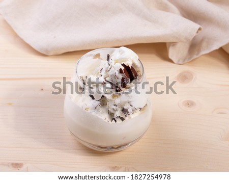 delicious creamy milky vanilla ice cream with caramel and chocolate addings in a glass container on the light rustic background