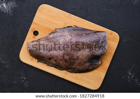 Top view of raw fresh halibut without head on wooden cutting board