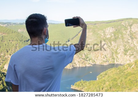 young man taking photo with mobile of the landscape of the ribeira sacra in orense, galicia, spain