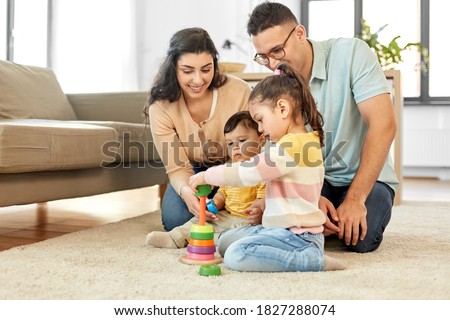 family and people concept - happy mother, father, little daughter and baby son playing with pyramid toy at home Royalty-Free Stock Photo #1827288074