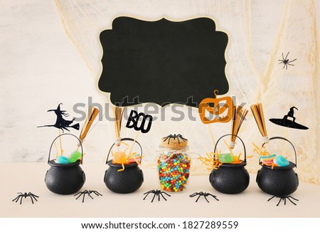 holidays image of Halloween. Witcher cauldron, broom, candies and spiders over white wooden table