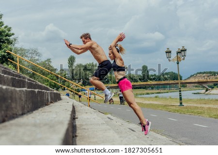 Side view picture of  active sporty couple jumping up on stairs in a park