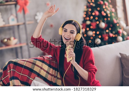 Photo of charming young lady hold sing telephone open mouth raise hand wear headphones red sweater in decorated living room indoors Royalty-Free Stock Photo #1827318329