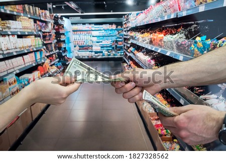 Hand passing money in supermarket. purchase concept