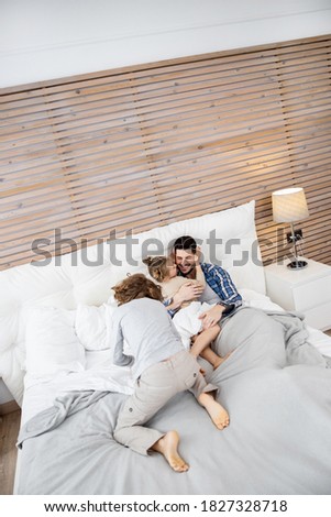 Happy family. Father playing with his two little children on the bed. Stock photo