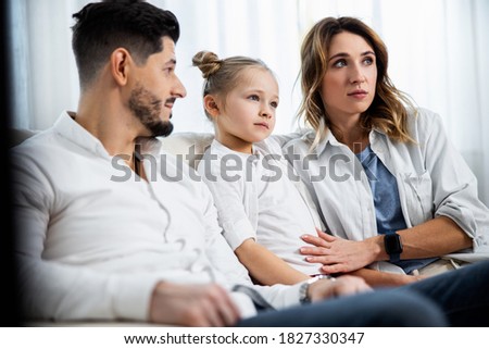 Family home leisure. Happy caucasian parents and their little daughter relaxing on couch together, enjoying weekend pastime, copy space