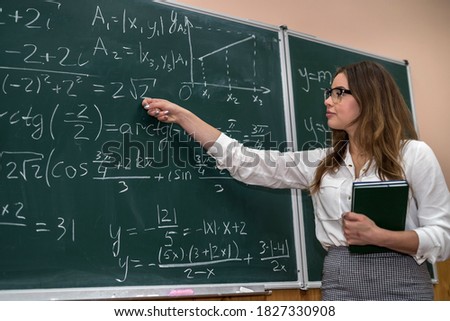 Young teacher writing and explain the mathematical formulas on a chalkboard.  Education