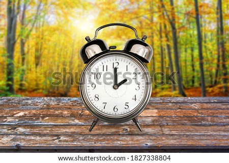 Vintage clock in a forest in autumn. Fall daylight savings time change concept