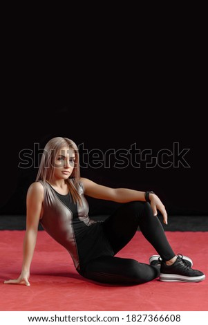 Healthy fitness woman in sportswear posing on camera whille sitting on the floor during workout in gym. Copy space