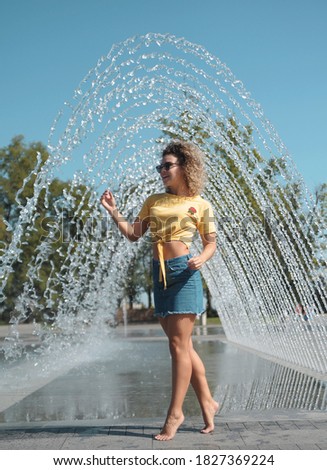 Young woman has fun in fountain outdoors. 