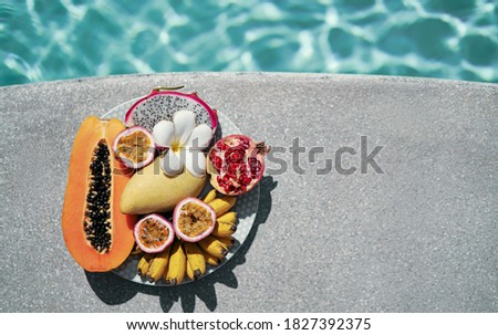 Vacation and diet concept. The plate of tropical exotic colorful fruits near water in swimming pool.