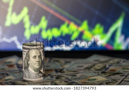 100 dollars curled up. Macro shot and background financial chart Royalty-Free Stock Photo #1827394793