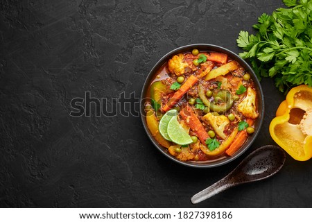 Veg Kolhapuri in black bowl on dark slate table top. Indian vegetable curry dish. Vegetarian asian food and meal. Copy space. Top view Royalty-Free Stock Photo #1827398186
