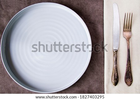 Empty tableware and dishware settings and serving on the gray background, plate, vintage folk and knife