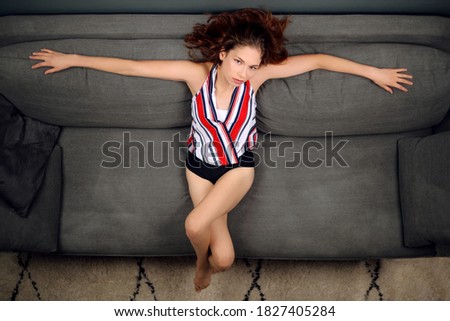 Attractive teenager woman smiling while relaxing on a sofa in her living room