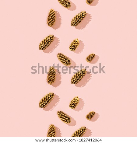 Christmas pattern from natural pine cone painted golden colored on pink. Trendy winter holiday background with copy space.