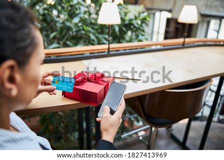 Focused photo on brunette woman that doing online shopping while being in cafe