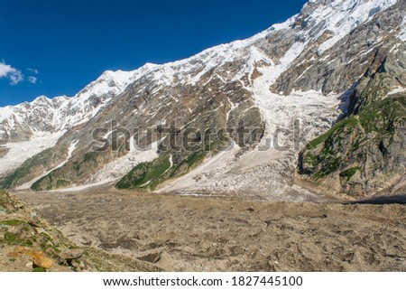 A large glacier covered with rocks and stones under the high mountain peak in Karakoram Range