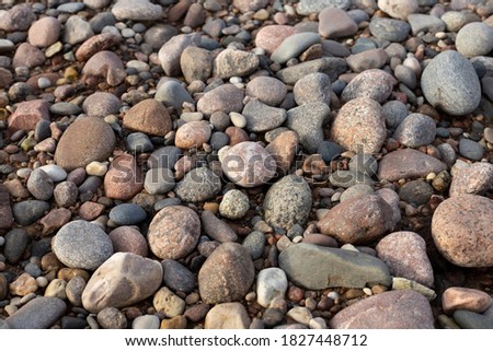 Beach coverd with medium sized granite rocks of different colors