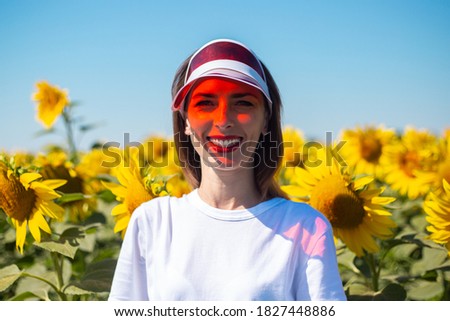 Young woman in red sun visor and white t-shirt on sunflower field