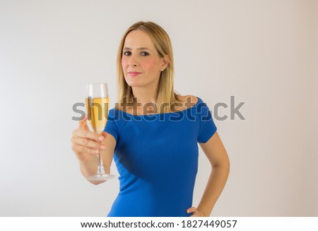 Young celebrating woman blue dress . Beautiful model portrait isolated over studio background hold wine glass.