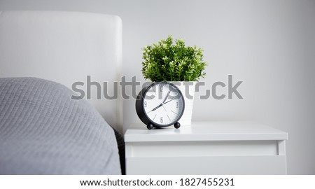 good morning concept - modern alarm clock and houseplant on bedside table