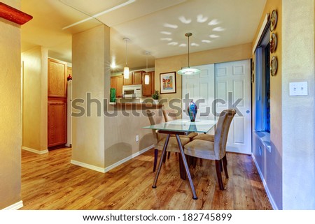 Small dining area with glass top table and chairs. View of kitchen room
