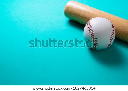 baseball and baseball bat on green table background, close up
