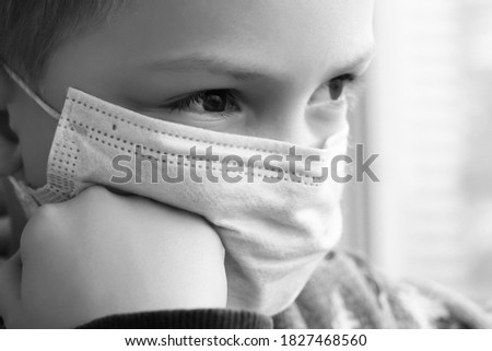 A little boy in a medical mask. Stays at home, self-isolation, Covid 2019. Black and white.