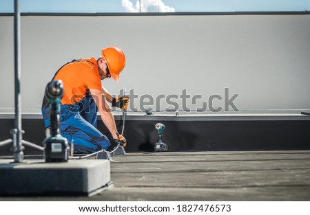 Caucasian Residential Building Lightning Protection System Installer in His 40s Finishing His Work on the Building Roof. 