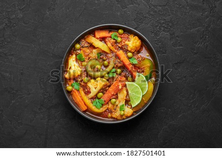 Veg Kolhapuri in black bowl on dark slate table top. Indian vegetable curry dish. Vegetarian asian food and meal. Top view Royalty-Free Stock Photo #1827501401