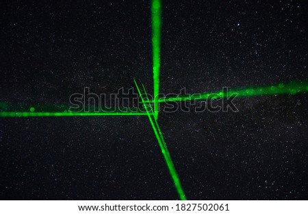 Green laser aimed at night sky with stars