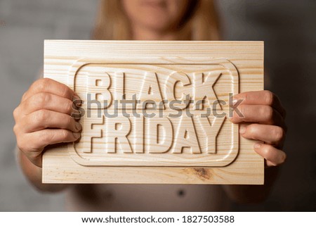 wooden sign with the words "Black Friday" in the hands of a girl