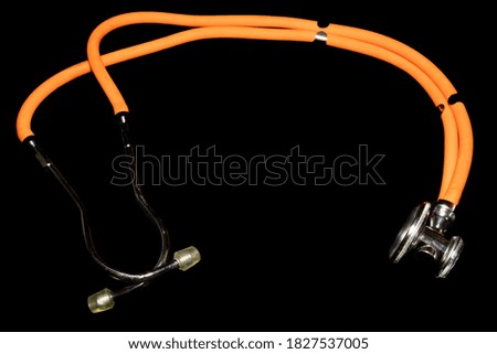 Orange stethoscope photographed on a black background.