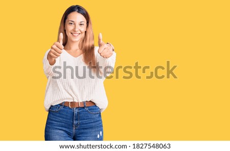 Beautiful young woman wearing casual clothes approving doing positive gesture with hand, thumbs up smiling and happy for success. winner gesture. 