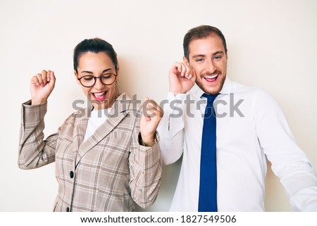 Beautiful couple wearing business clothes dancing happy and cheerful, smiling moving casual and confident listening to music 