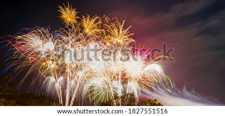 A low angle shot of many fireworks in groups at night. There is dazzlingly lit and colorful. Feeling fun and happy. The idea for celebration wallpaper with copy space on the right of the picture.