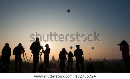 Photographers in action- a group of people in silhouette shooting the hot air balloons in the sky during sunrise