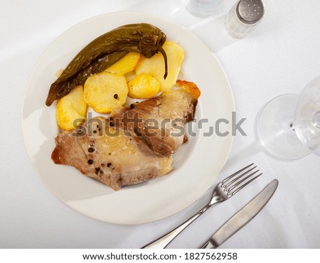 Close up of tasty baked pork with potatoes, served on plate