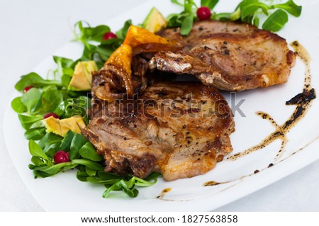 Cooked fried pork meat chops with with greens, avocado and berries at plate