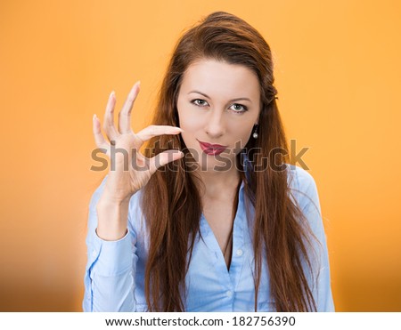 Closeup portrait of beautiful young woman showing small amount gesture with hands, isolated on orange background. Negative human emotion facial expression feelings, body language, signs, symbols